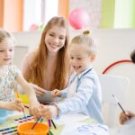 Young children enjoy painting with a teacher in a vibrant classroom setting.